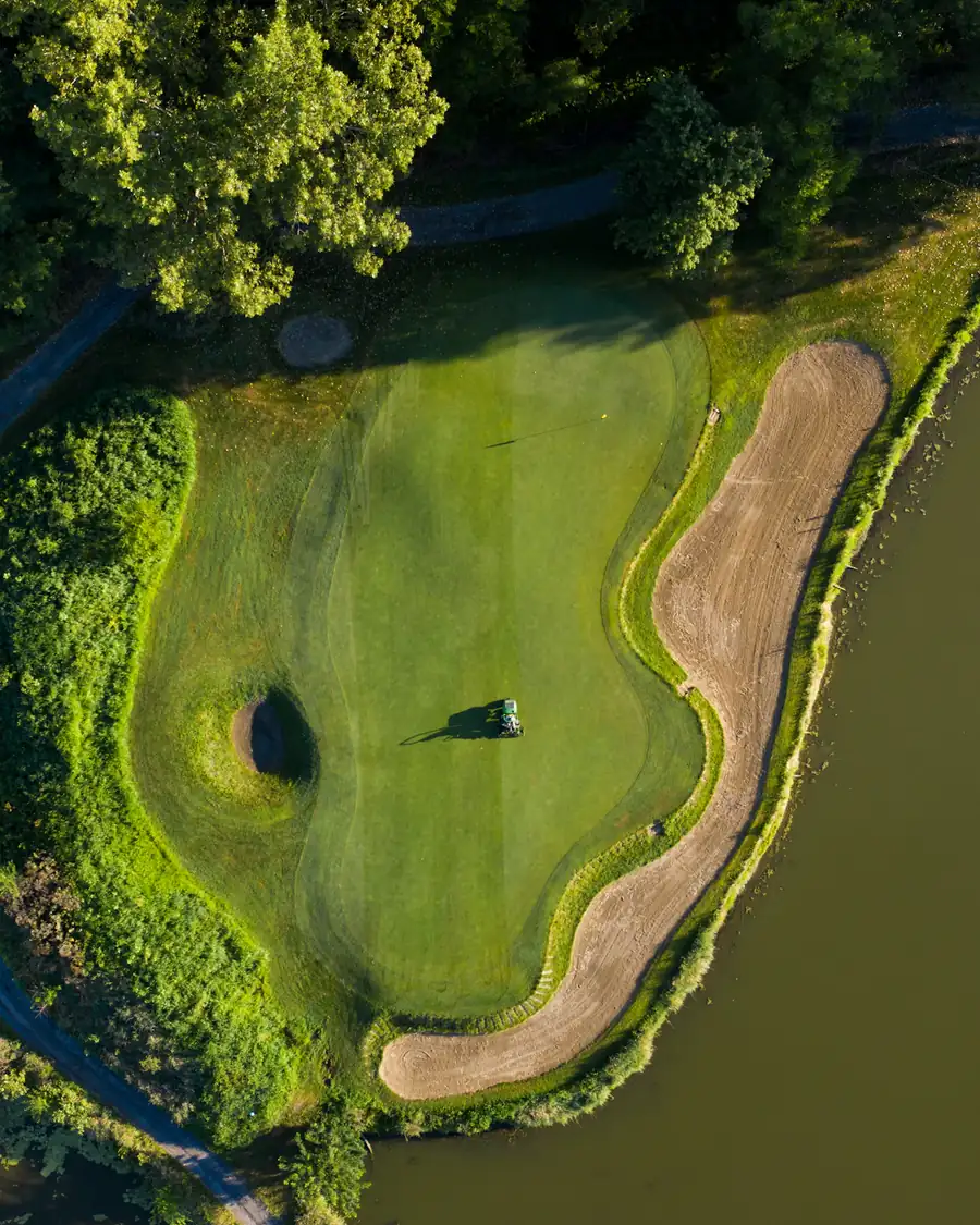 Aerial view of a green surrounded by water and trees
